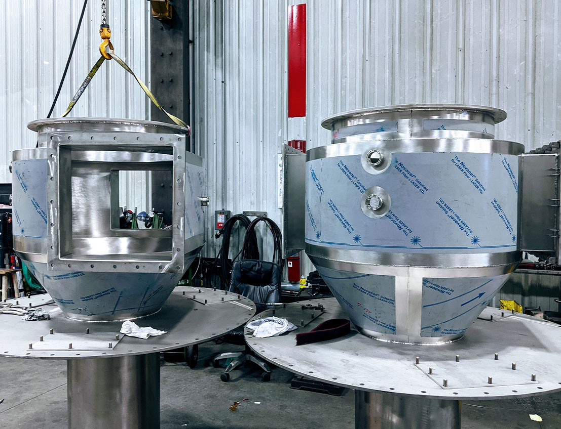 Silver stainless steel miniaturized cyclones for spray drying and other processes, custom fabricated to perfectly fit tank lids. Food and pharmaceutical-grade stainless steel is fabricated in dedicated bays to prevent contamination and maintain quality.