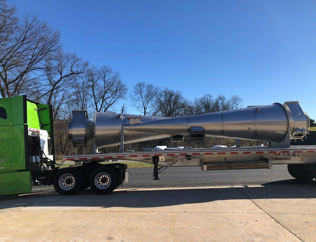 stainless steel cyclone dryer laying horizontally on a 53 foot flatbed, leaving for delivery