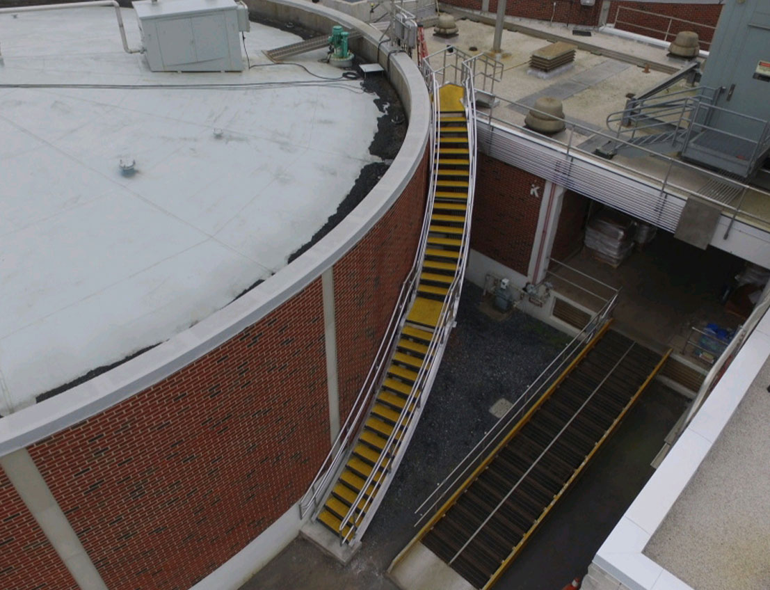Structural Stairs shown on water tower for water/wastewater industry. Osha compliant yellow sstairs and stainless