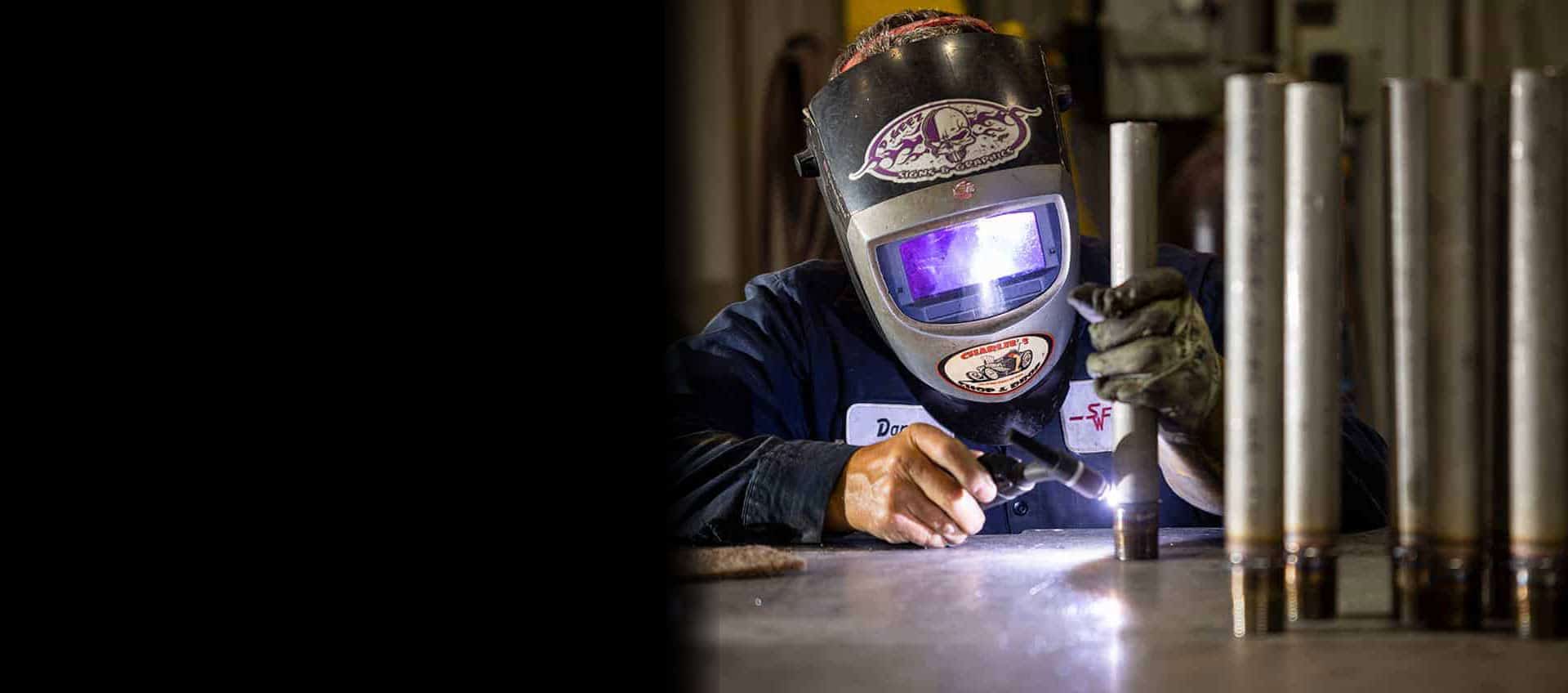 SWF employee in welding helmet welds piping with precision and safety