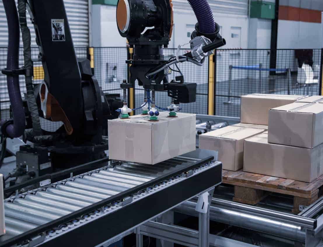Automated robotic arm loading cartons on a conveyor belt