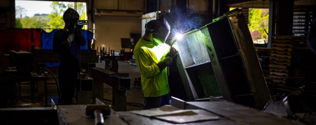 SWF industrial employee welding a sheet metal cabinet in a shop
