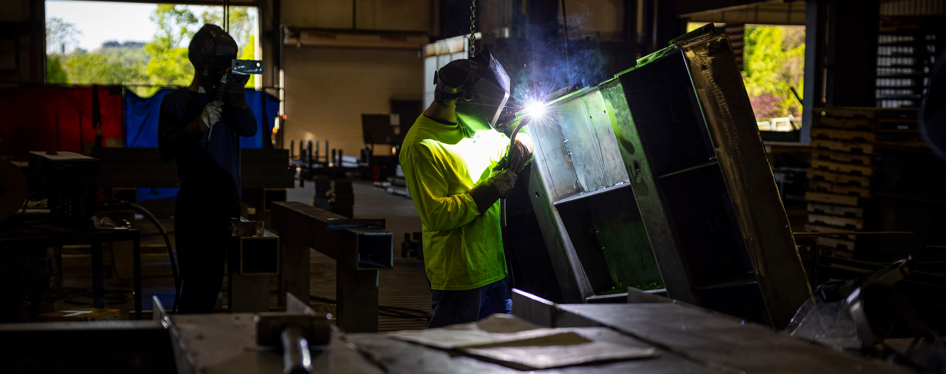 industrial employee welding a sheet metal cabinet in a shop
