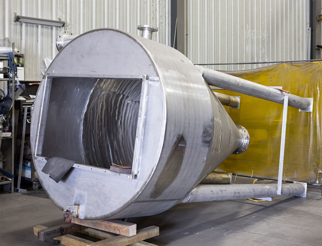 Stainless steel storage hopper on tube steel legs laying on it's side before final assembly