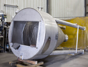 Stainless steel storage hopper on tube steel legs laying on it's side before final assembly