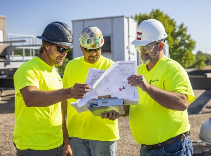industrial field service workers reviewing plans for a stainless steel hvac installation