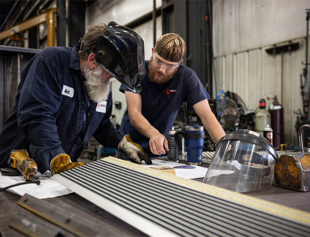 two welders reviewing a design for a metal fabrication project
