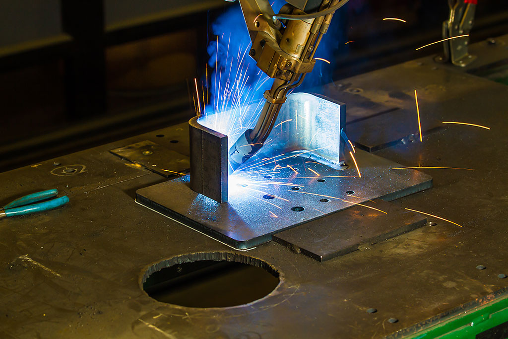 One use of AI in manufacturing in action, showing an automated welder finishing a part, reducing repetitive work.